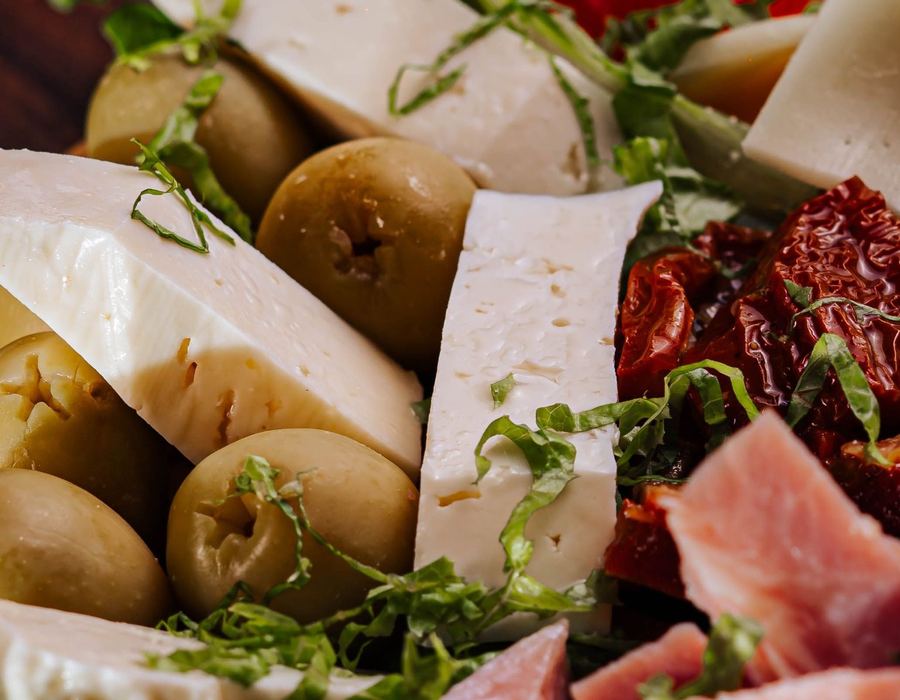 Detalle de quesos, aceitunas y tomates secos de una picada